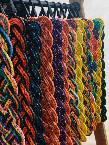 Hanging vibrant colored welcome mats made with upcycled lobster rope