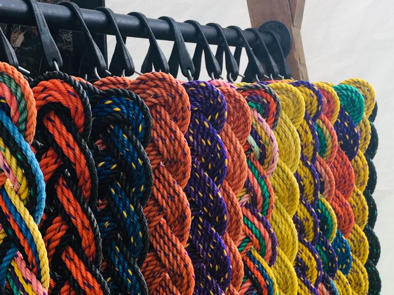 Hanging vibrant colored welcome mats made with upcycled lobster rope